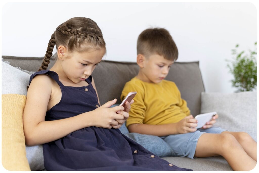 Jakie są przyczyny powstawania wad postawy? Co mówią badania naukowe Dzieci siedzące w pozycji siedzącej z pochyloną głową podczas korzystania z telefonów, co może sprzyjać nieprawidłowej postawie ciała.